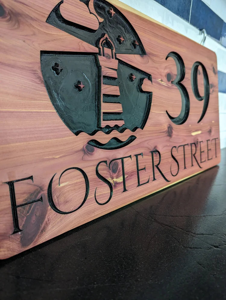 Wooden sign with a ship emblem and text 'Foster Street 39' on a dark surface.