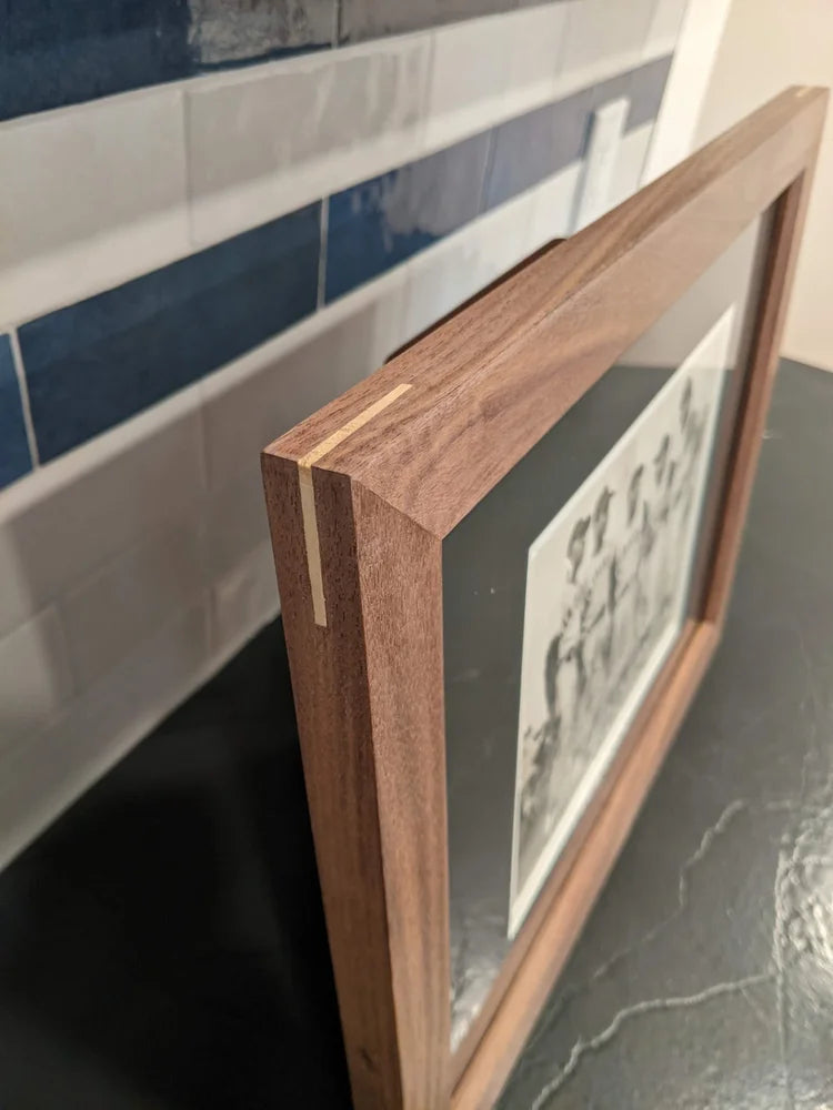Wooden picture frame leaning against a tiled wall.