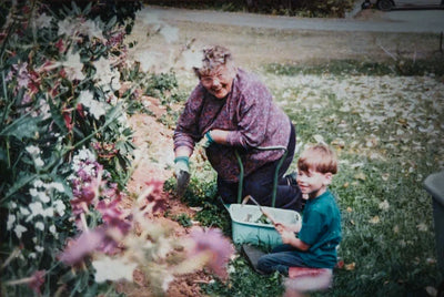 Woman and child gardening together in a garden with flowers and plants.