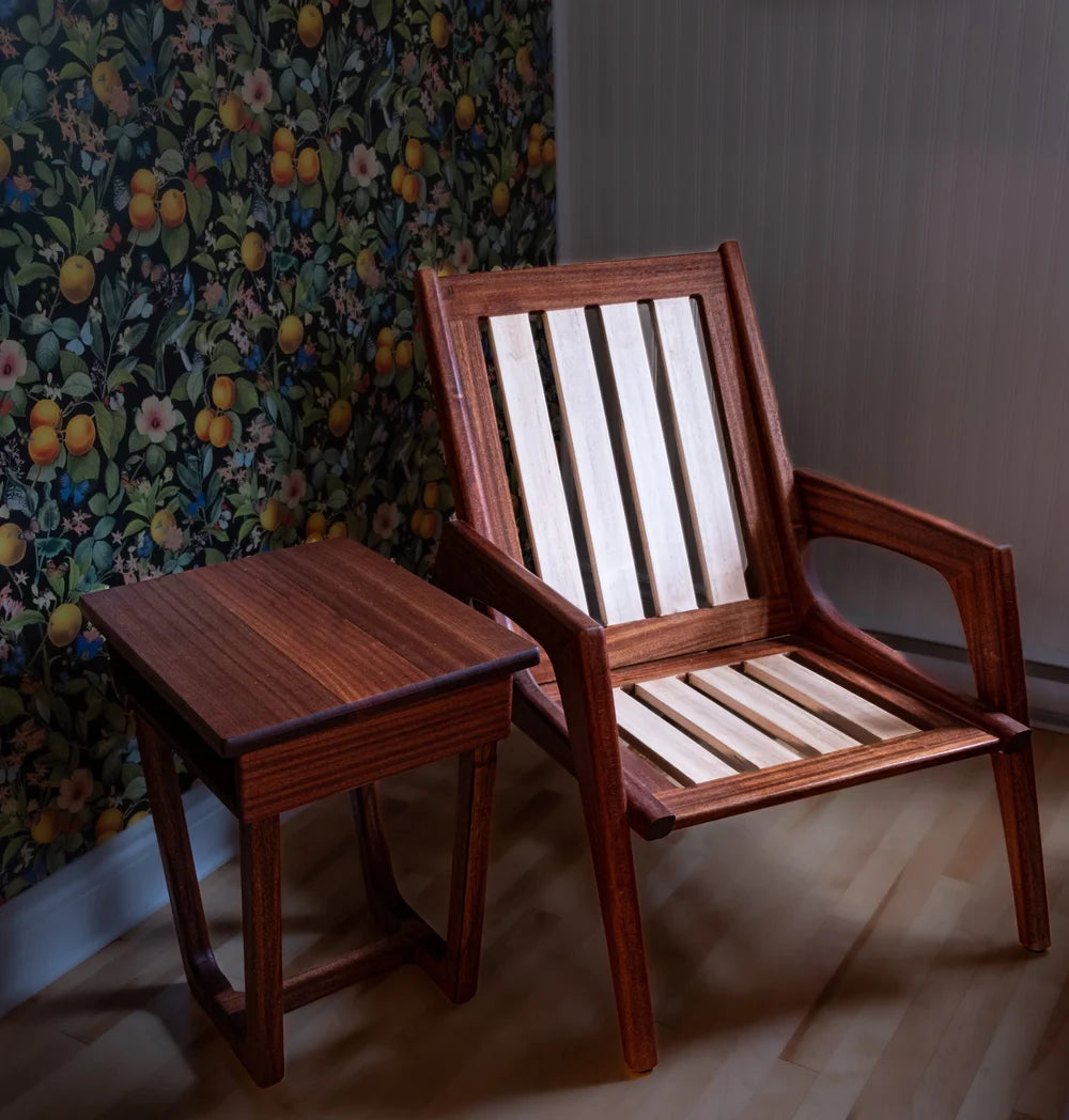 Wooden chair and side table against a floral wallpapered wall