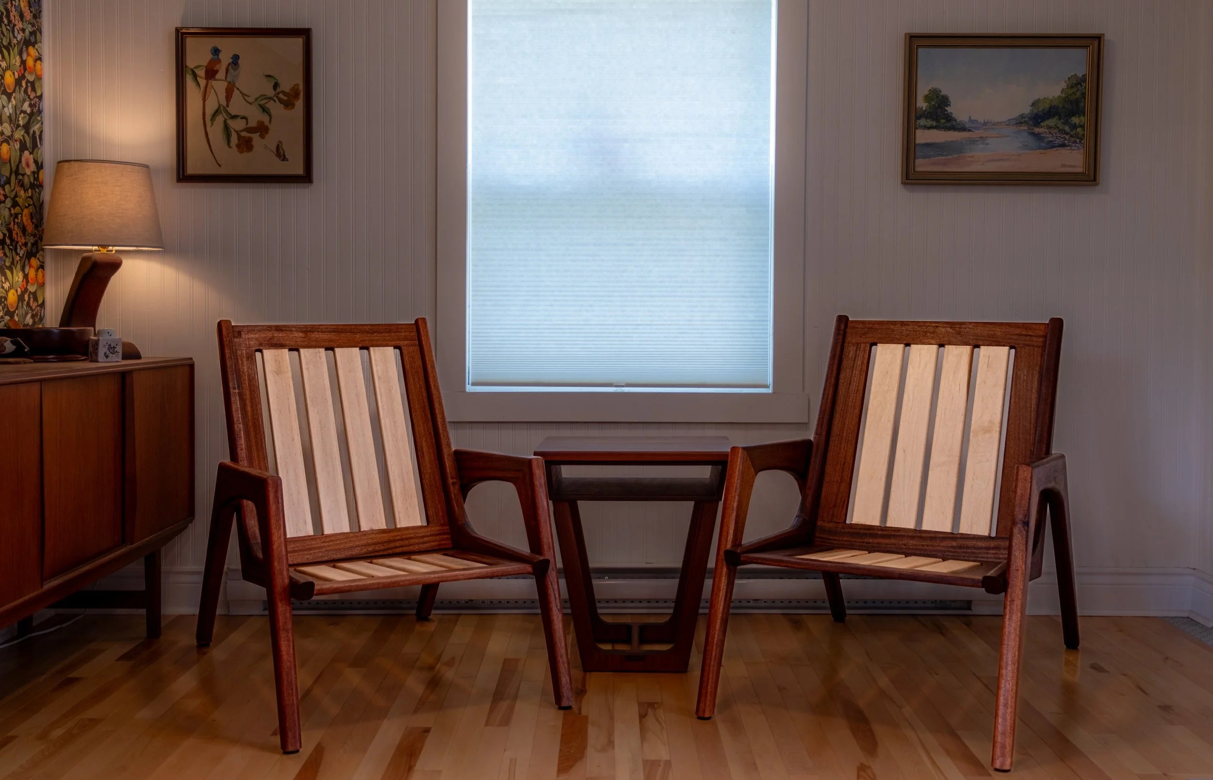 Two wooden chairs with striped cushions in a room with a window and wall art.