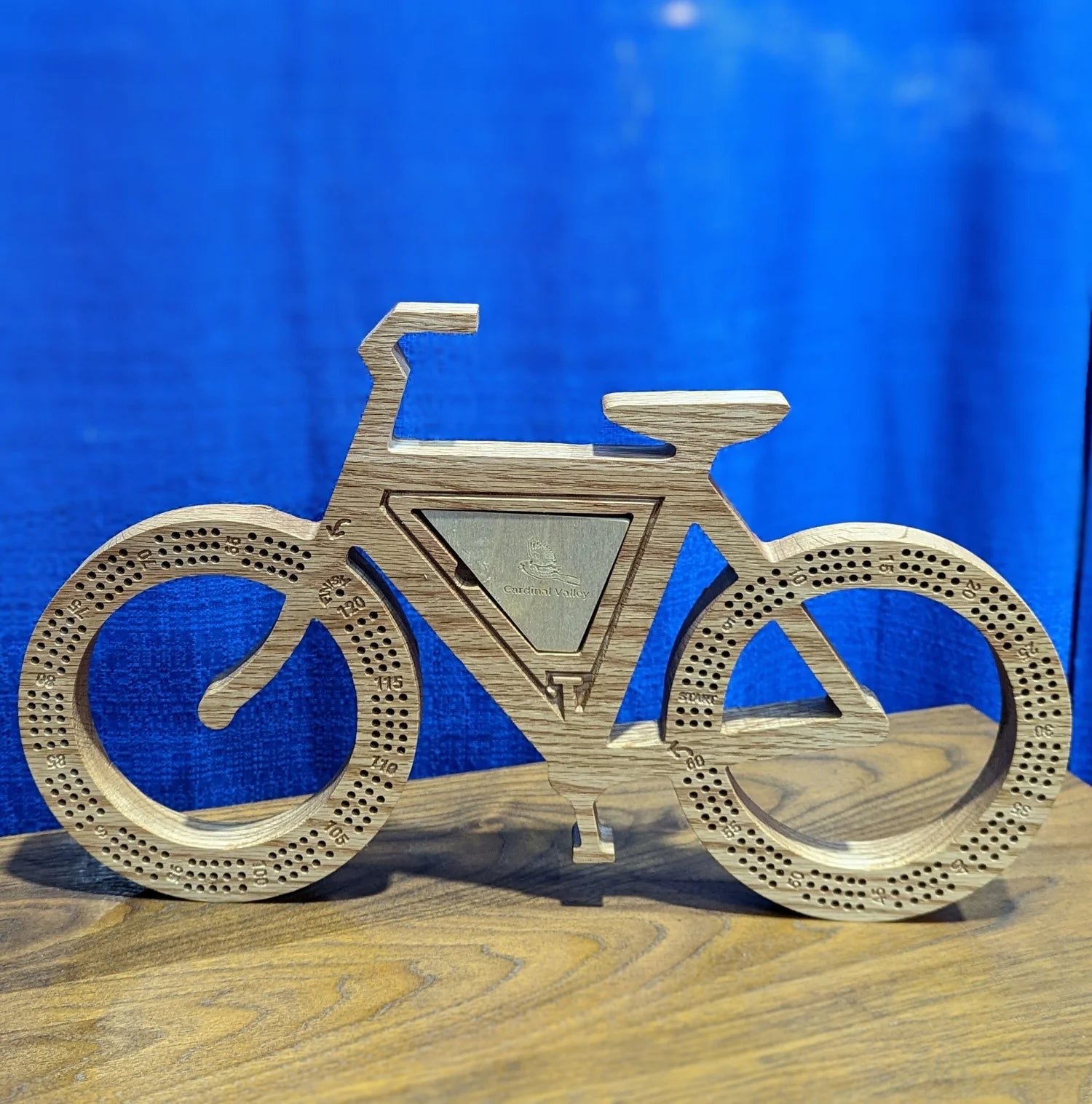 Wooden bicycle model on a wooden surface with a blue background