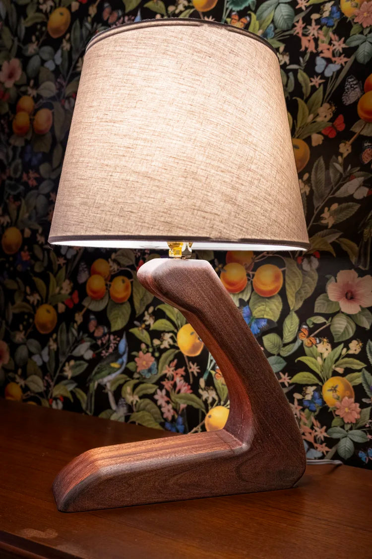 Wooden lamp with a beige lampshade on a floral-patterned background