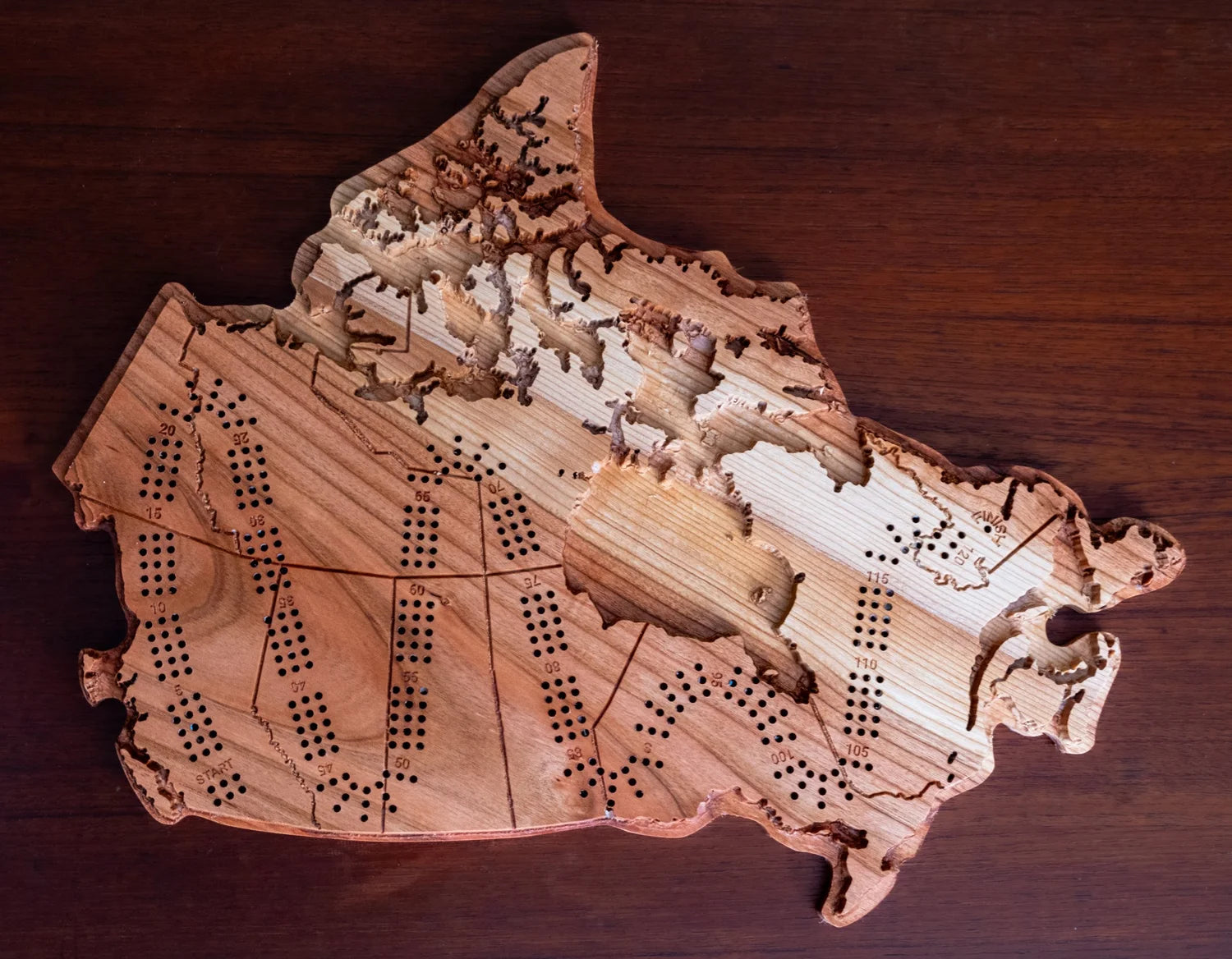 Wooden Canada-shaped cribbage board on a wooden surface