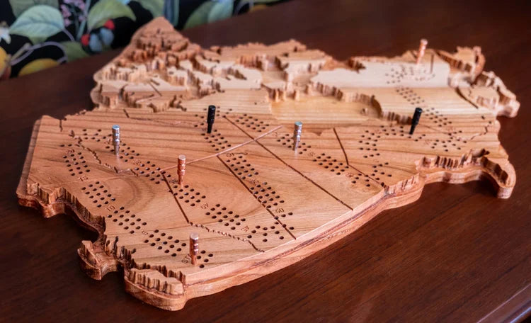 Wooden cribbage board shaped like a ship on a wooden surface