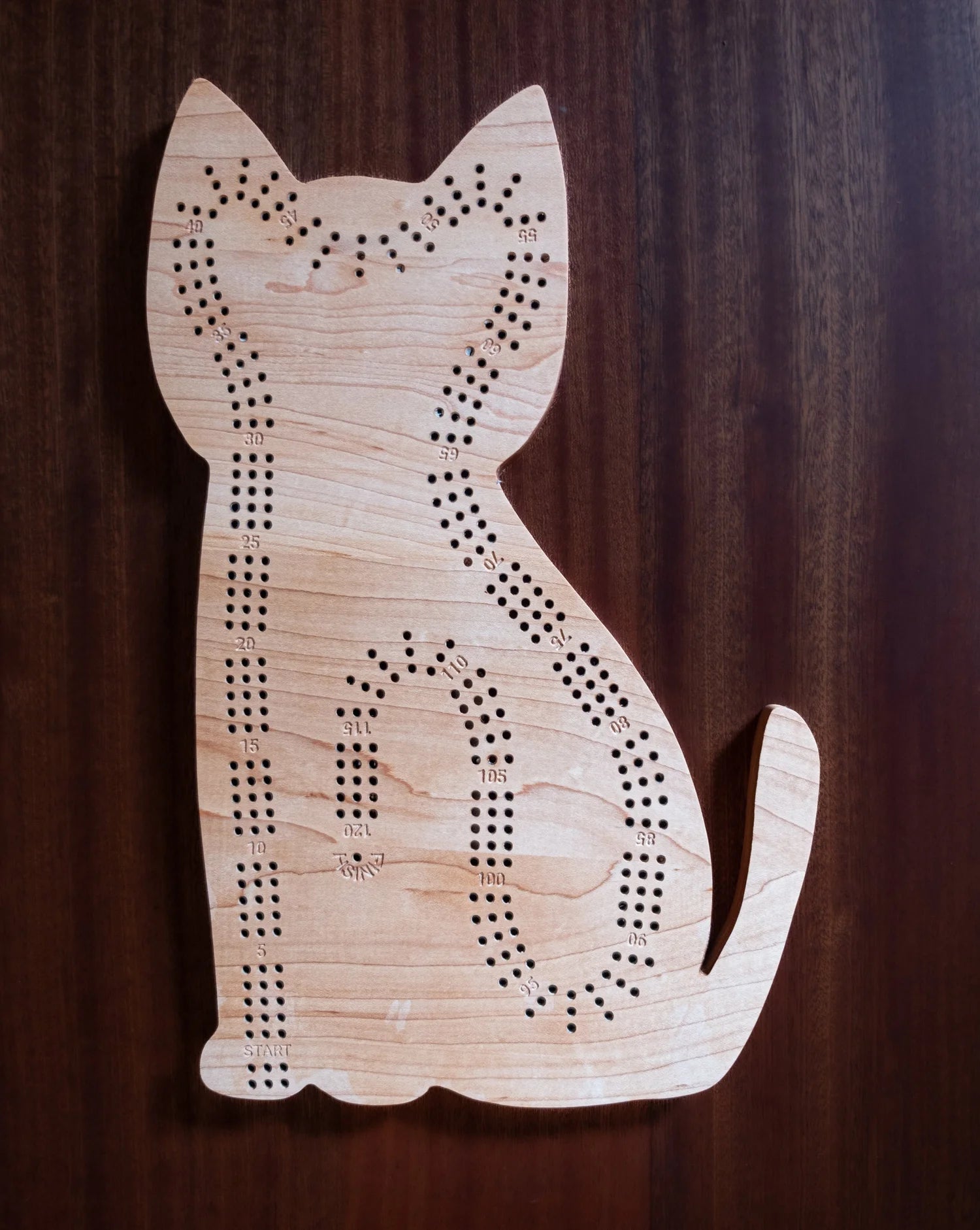 Wooden cat-shaped cribbage board on a dark background