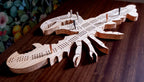 Wooden lobster-shaped cribbage board on a wooden surface with a colorful background.