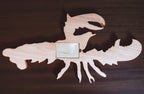 Wooden lobster-shaped cribbage board on a wooden surface