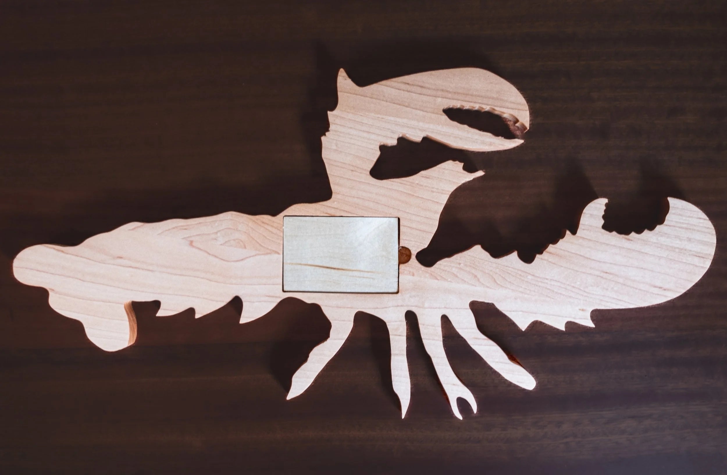 Wooden lobster-shaped cribbage board on a wooden surface