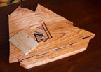 Wooden ship-shaped cribbage board on a floral background with fruits.