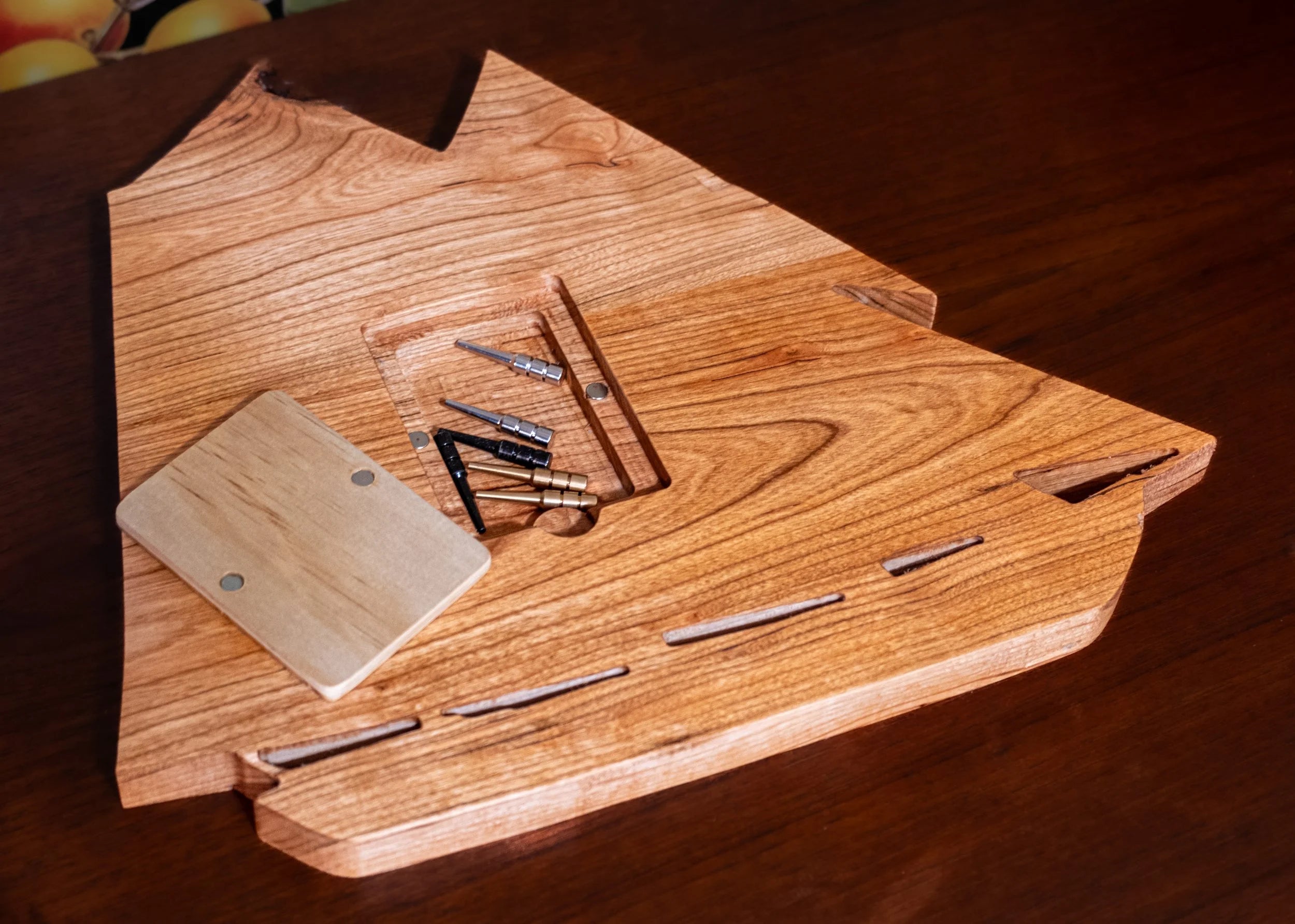 Wooden ship-shaped cribbage board on a floral background with fruits.