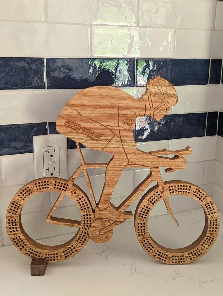 Wooden sculpture of a cyclist on a bike against a tiled wall.