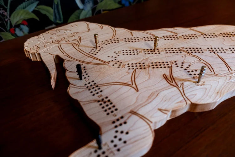 Wooden cribbage board with pegs on a wooden surface