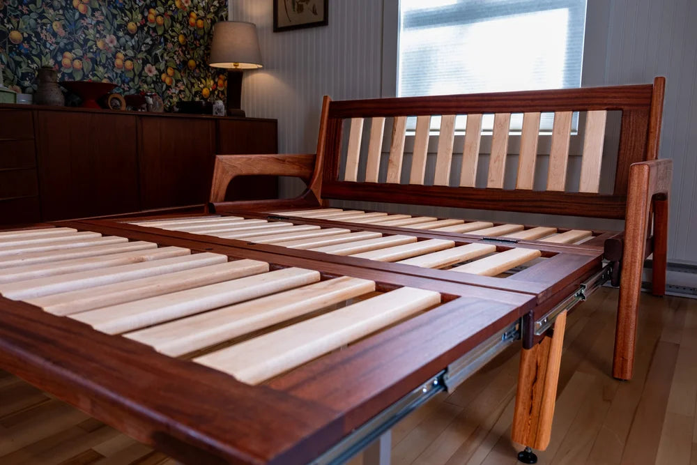 Wooden bed frame with adjustable slats in a room setting.