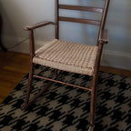 Wooden rocking chair with woven seat on a patterned rug
