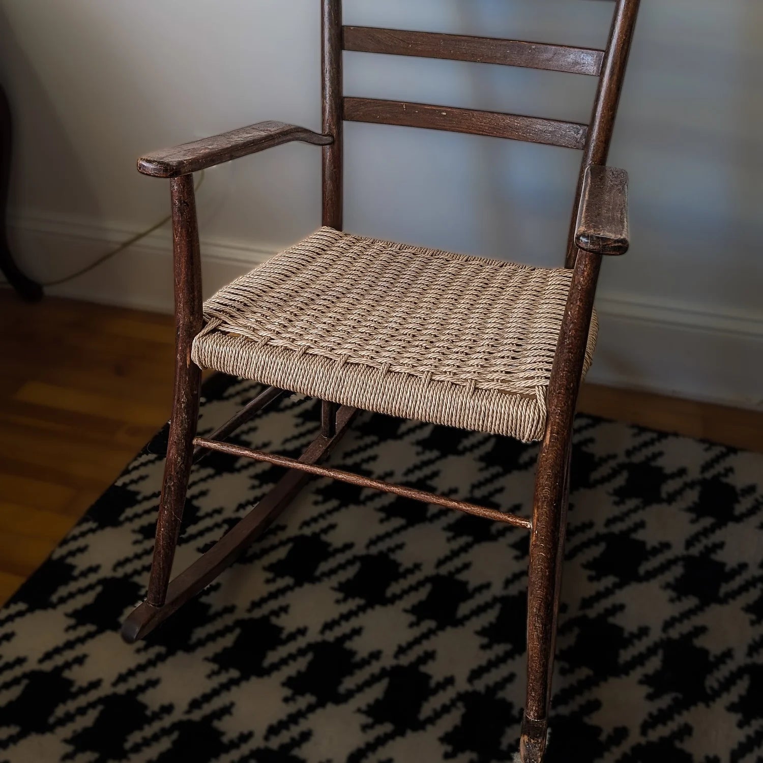 Wooden rocking chair with woven seat on a patterned rug