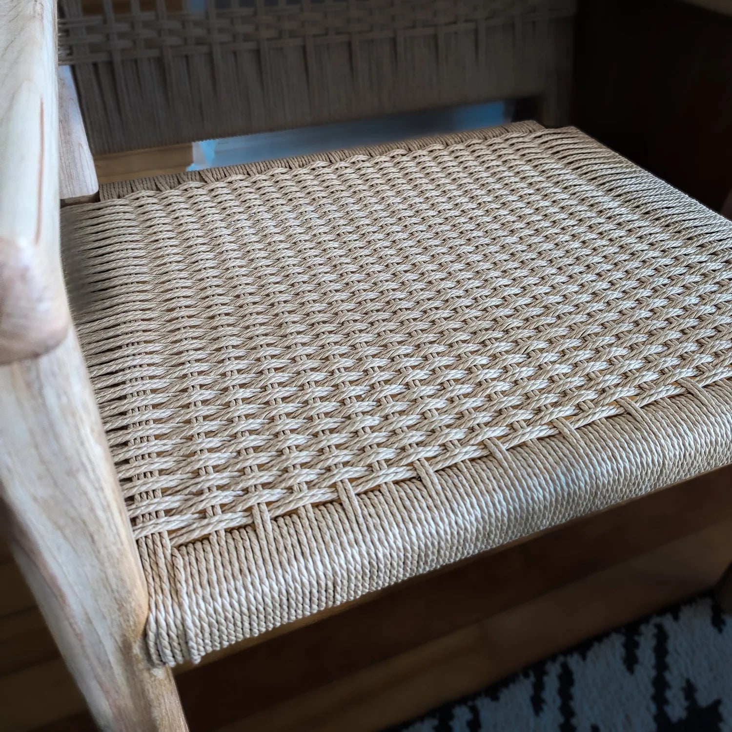 Close-up of a woven chair seat with a wooden frame.