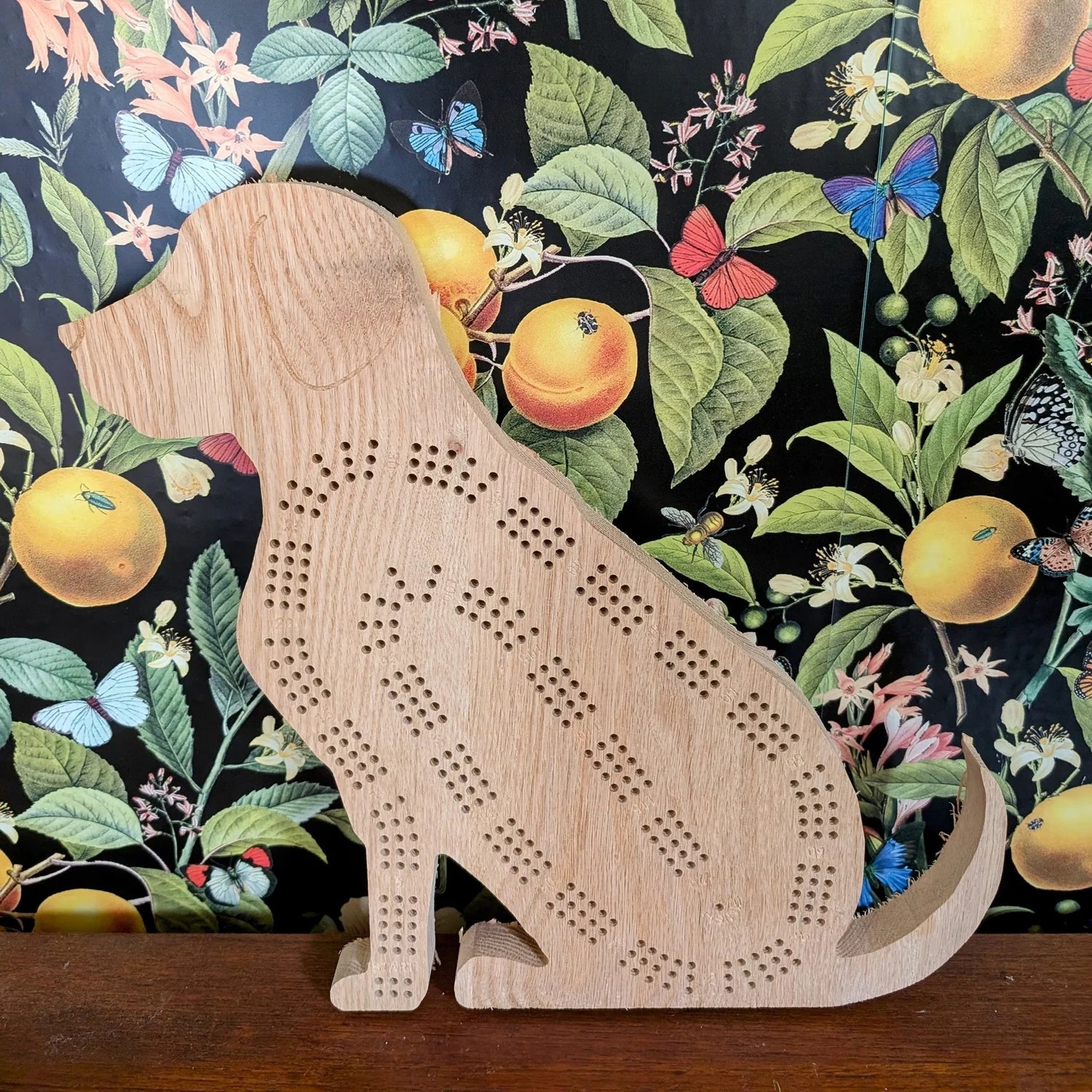 Wooden dog-shaped cribbage board on a floral-patterned background
