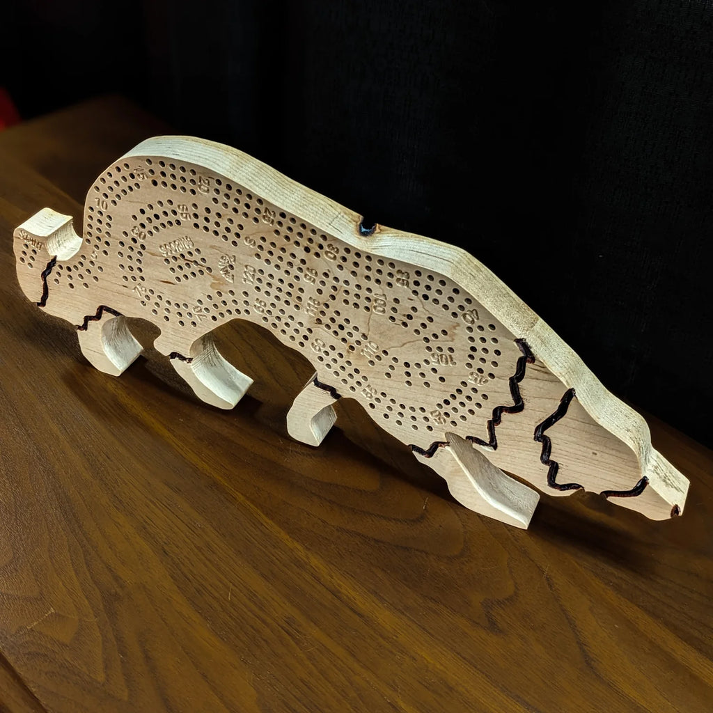 Wooden dog-shaped cribbage board on a wooden surface with a dark background
