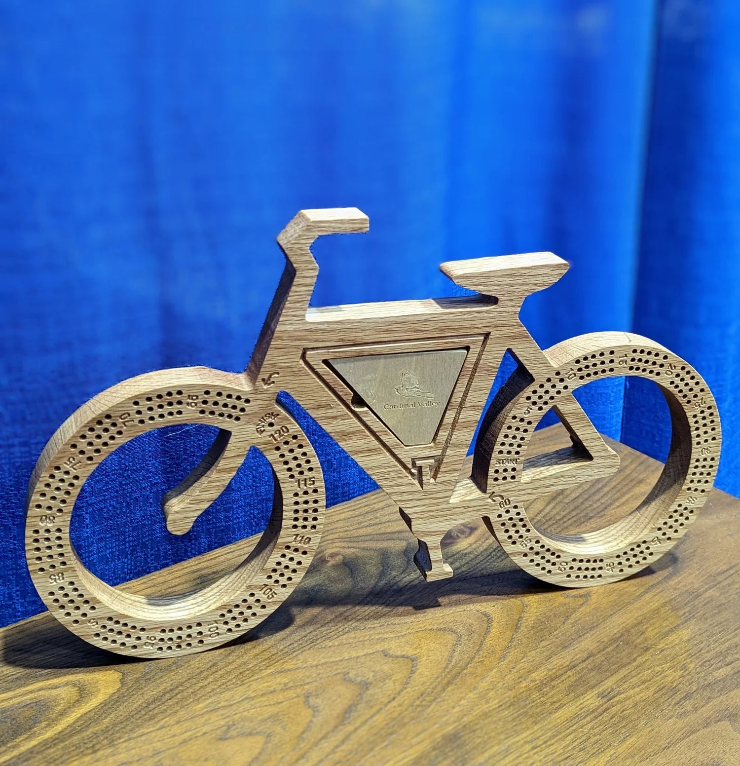 Wooden bicycle model on a wooden surface with a blue background