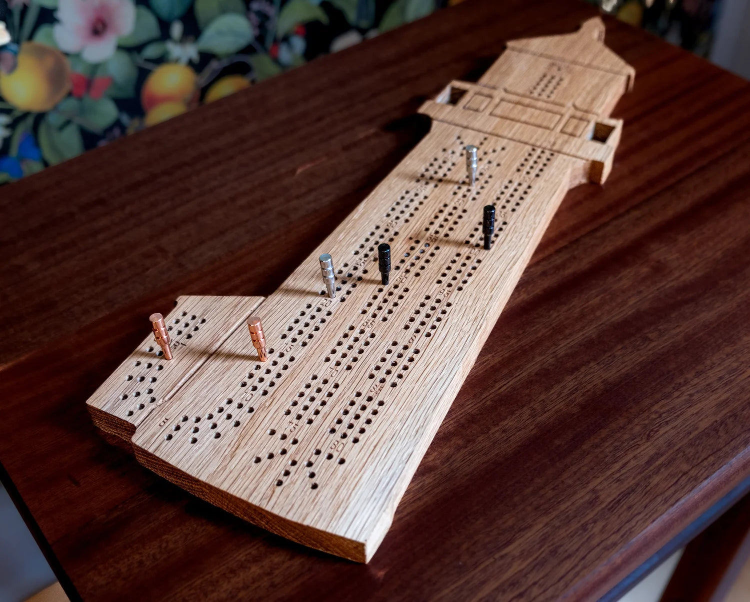 Wooden cribbage board with pegs on a wooden surface
