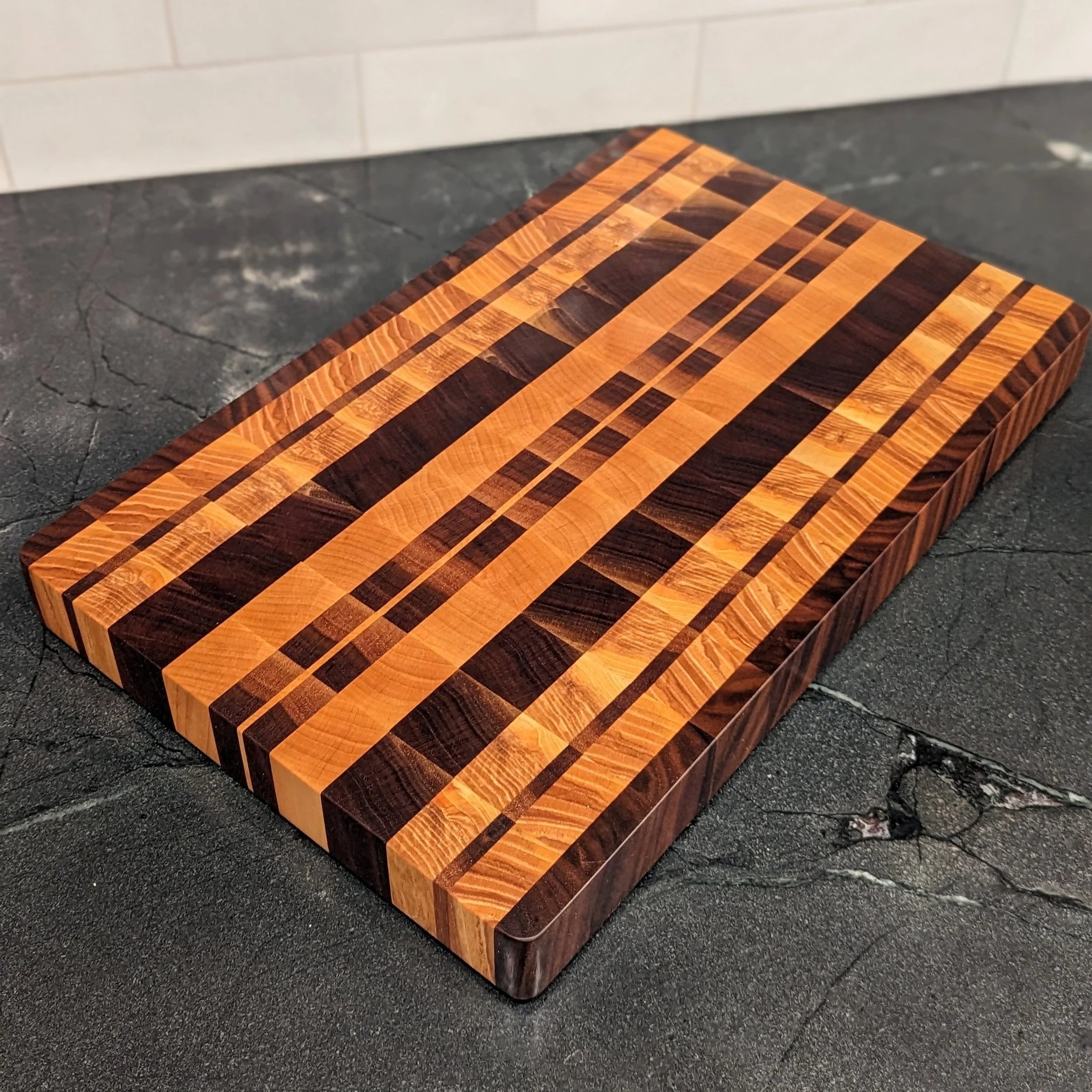 Wooden cutting board with striped pattern on a dark surface