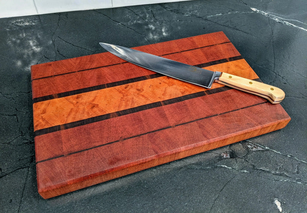 Wooden cutting board with a large knife on a dark surface