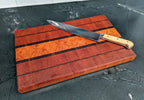 Wooden cutting board with a large knife on a dark surface