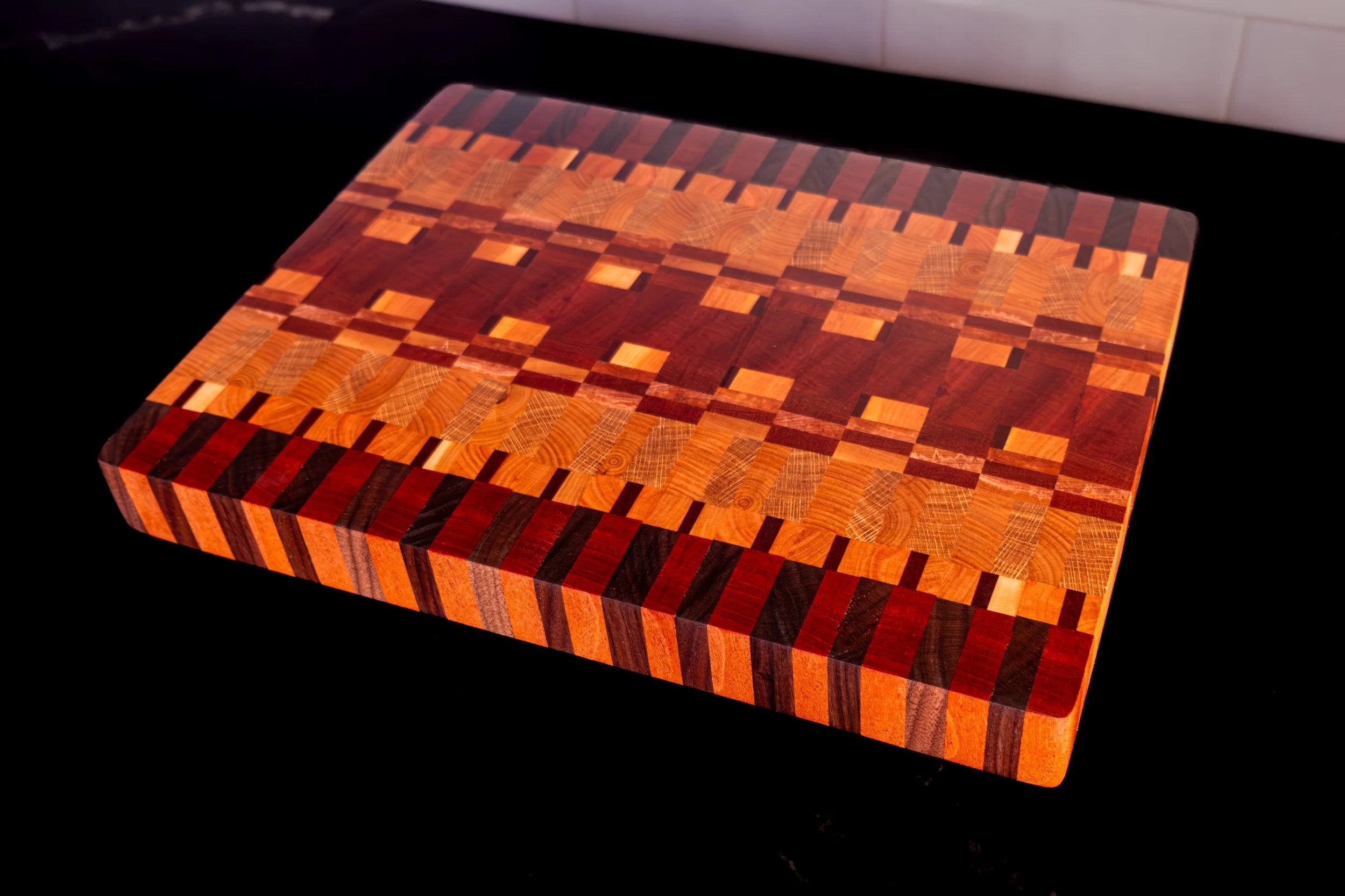 Wooden cutting board with a geometric pattern on a black surface.