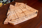 Wooden cribbage board on a wooden surface with fruits in the background