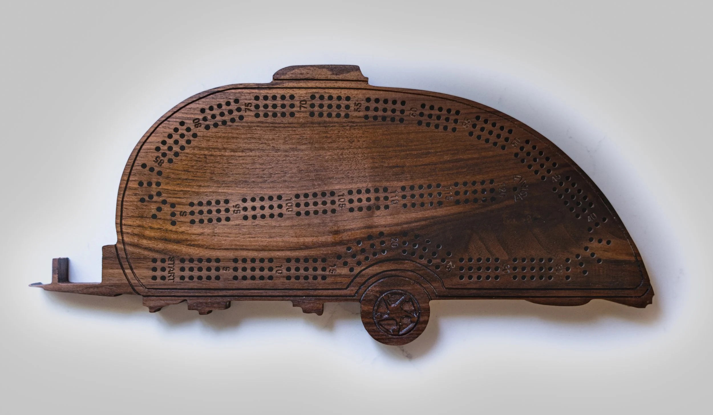 Wooden cribbage board shaped like a camper on a white background