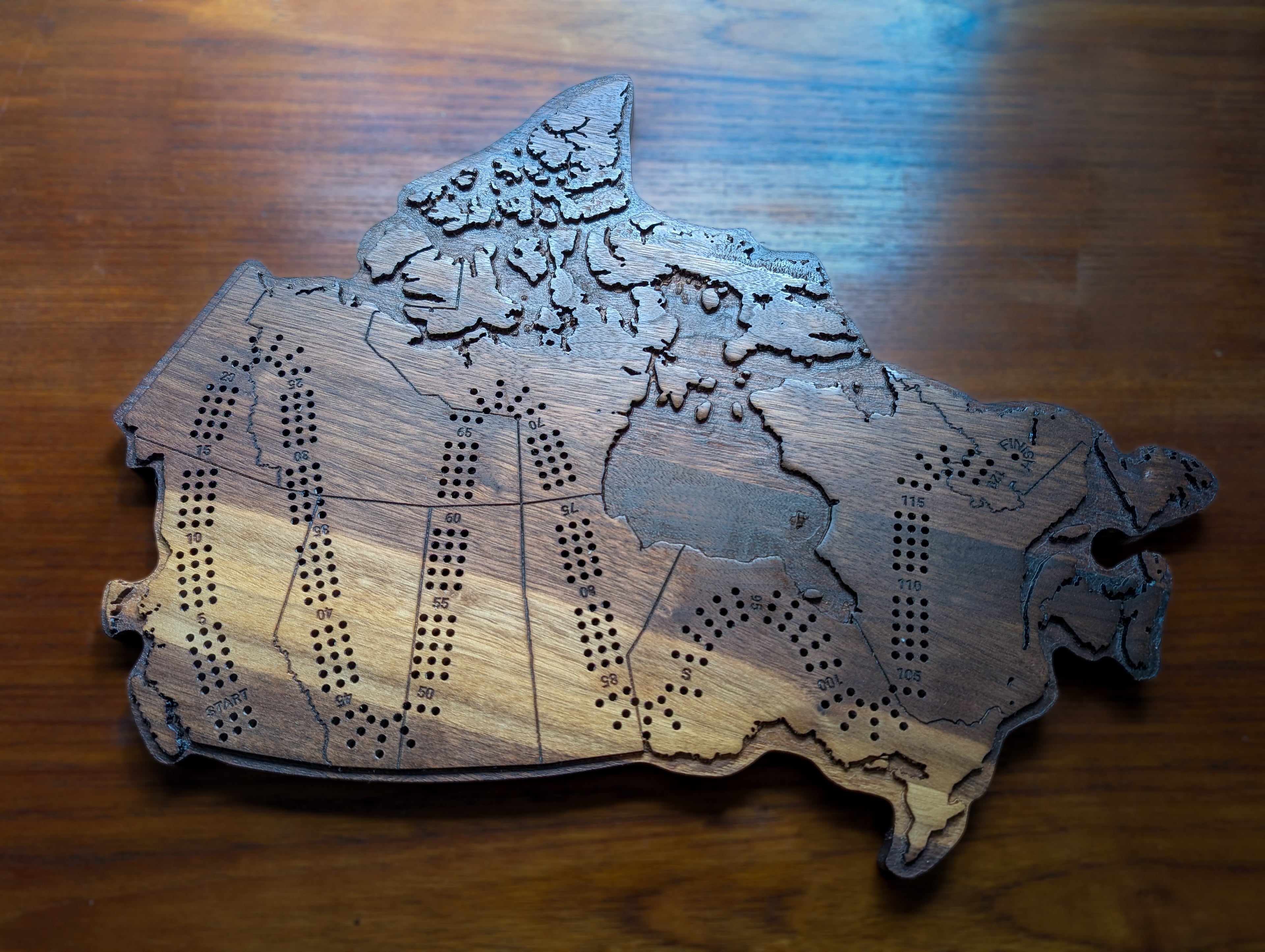 Wooden cribbage board in the shape of the map of Canada.