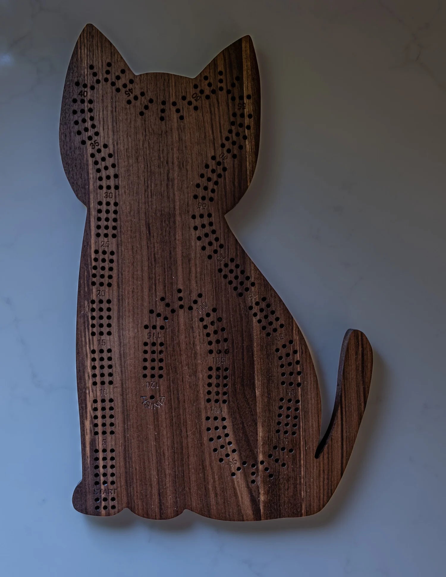 Wooden cat-shaped cribbage board on a light background