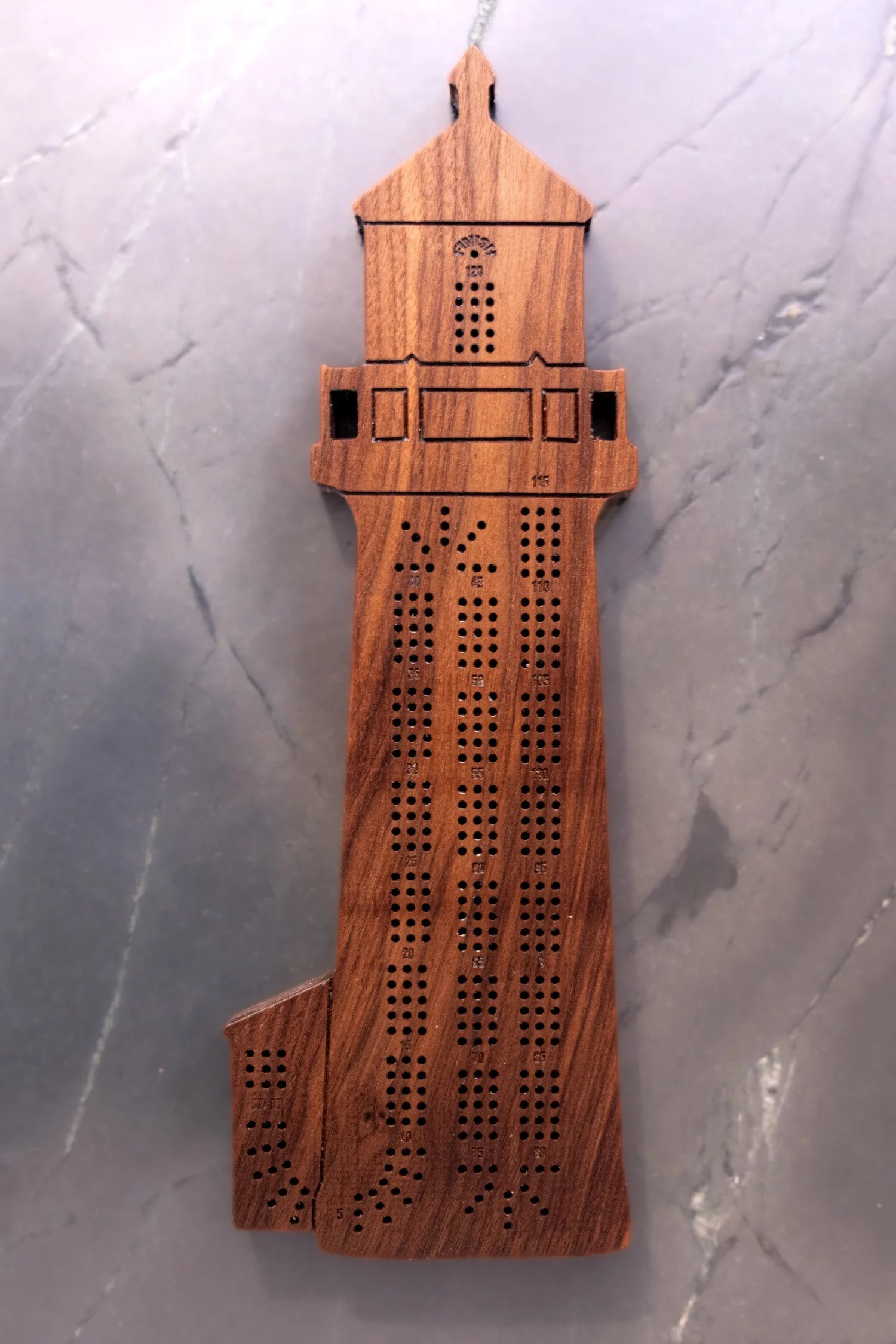 Wooden lighthouse cribbage board on a gray surface