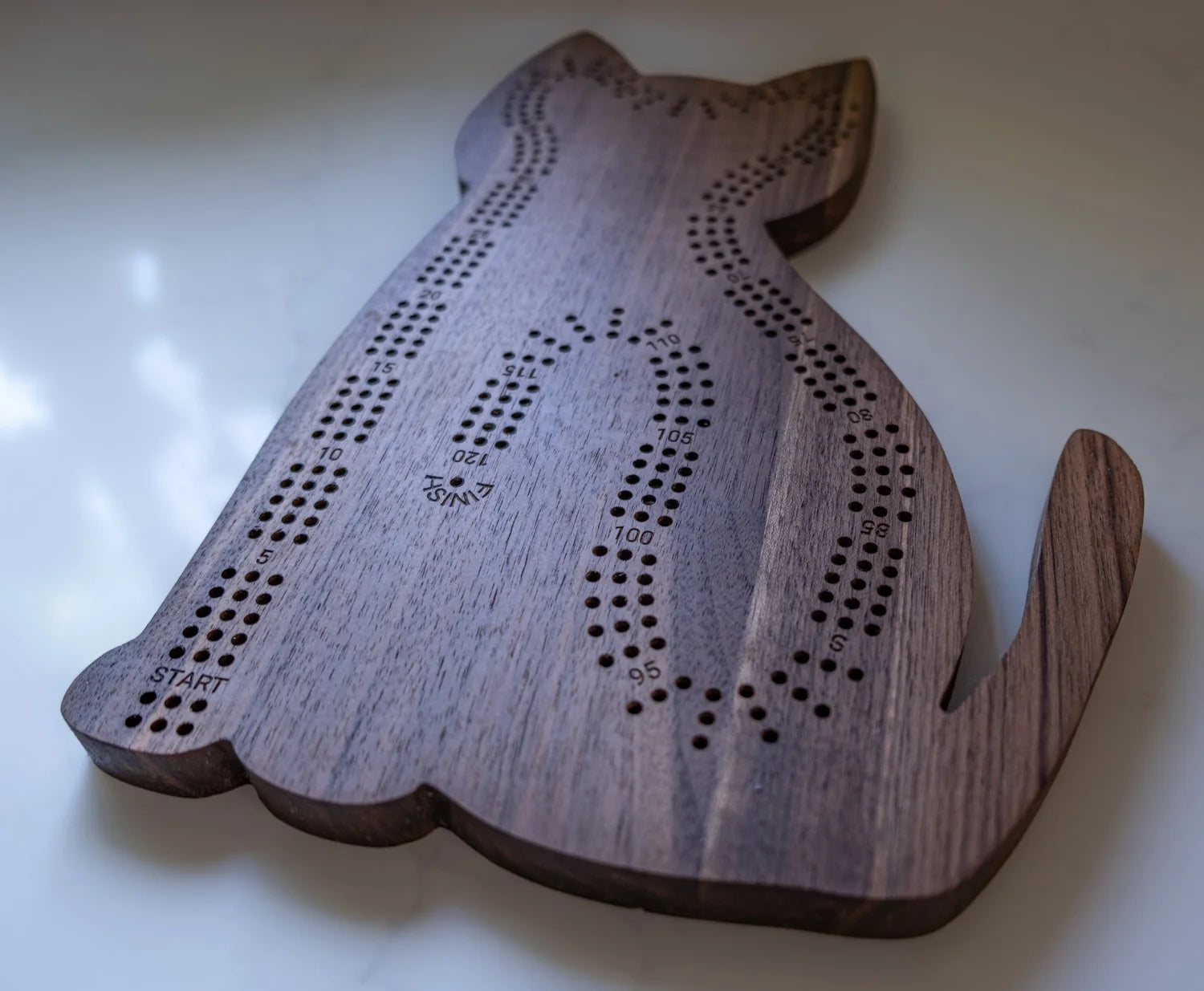 Wooden cat-shaped cribbage board on a white surface
