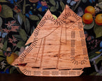 Wooden ship-shaped cribbage board on a floral background with fruits.