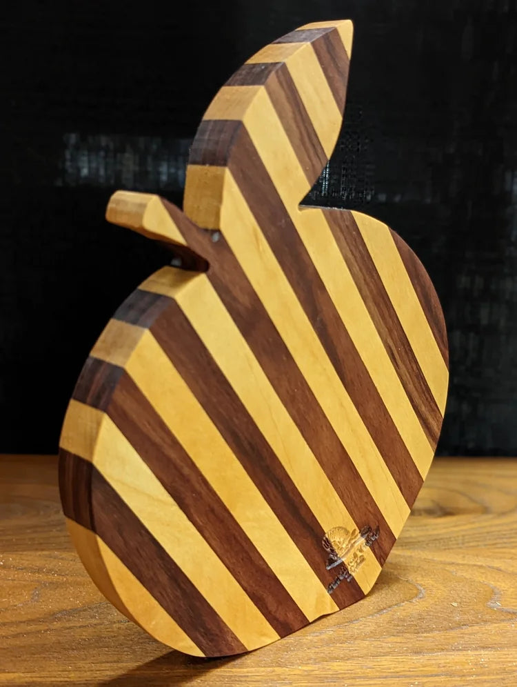 Wooden board shaped like a peach on a wooden surface with a dark background